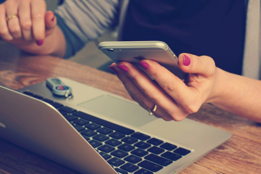 Person shopping on a phone beside a laptop